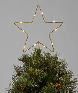 An LED lit, glittery metal gold star-shaped Christmas tree topper