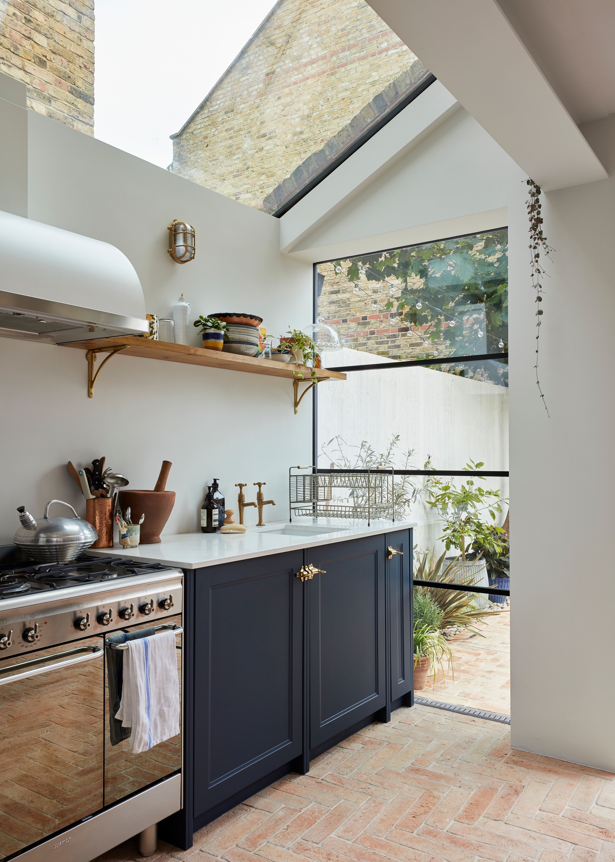 white kitchen with terracotta floor tiles and blue kitchen cabinets