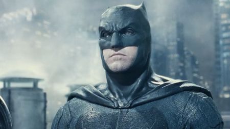 Batman (Affleck) stands on top of a Gotham skyscraper with lighting all around in Zack Snyder's Justice Leauge. 