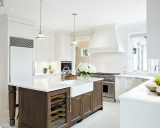 Kitchen layout ideas with U-shaped layout with white cabinetry, and wooden island in the centre with white marble top