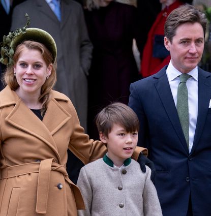 Princess Beatrice wearing a tan coat standing with her arm around her stepson, standing next to Edoardo Mapelli Mozzi