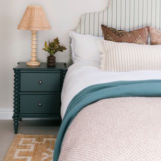 A guest bedroom with the bed layered with patterned scatter cushions and throws and a jute rug on the floor