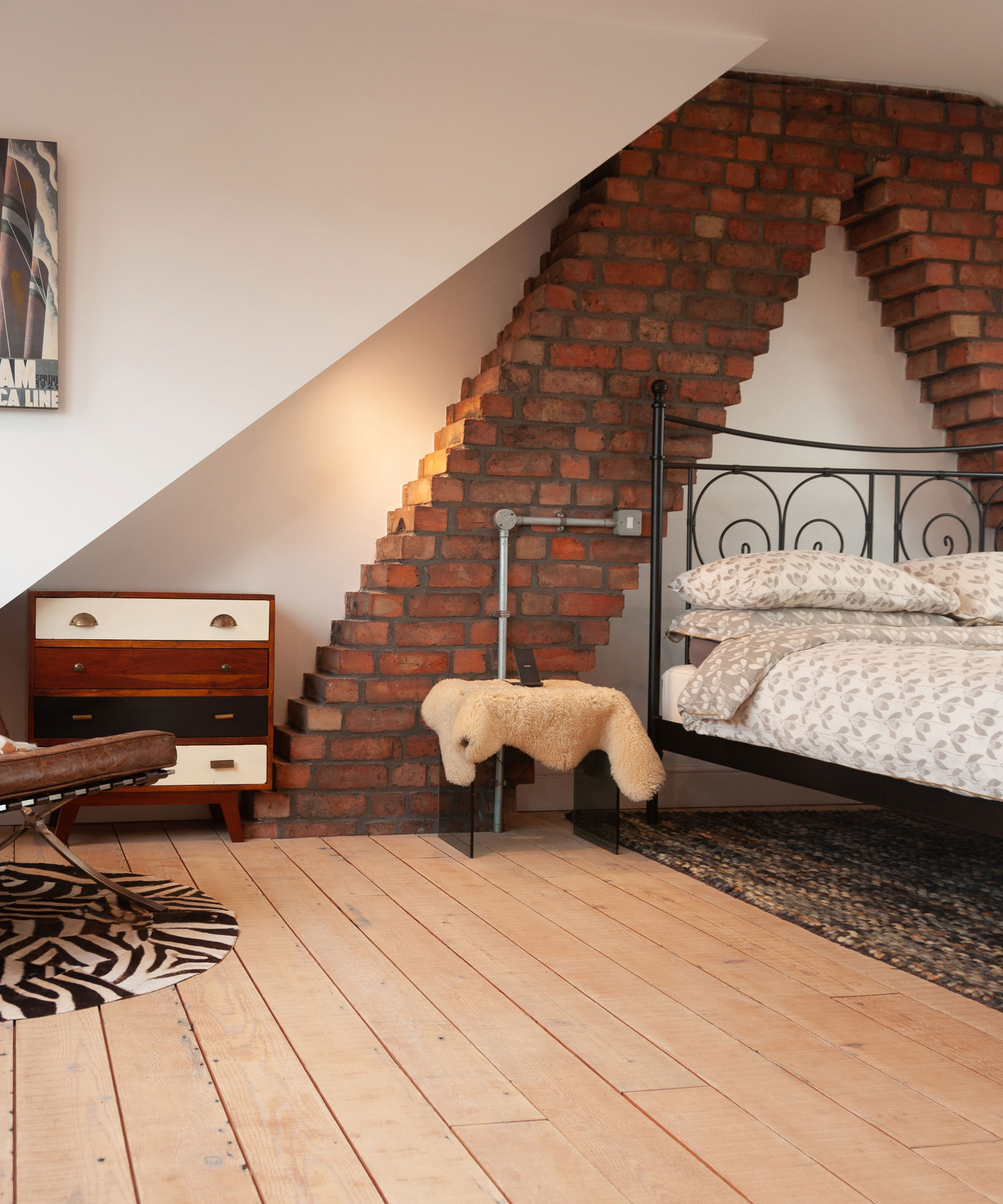 loft bedroom with wooden flooring and exposed chimney stacks