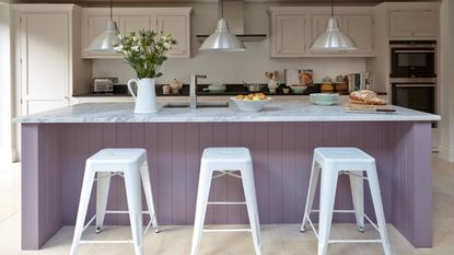 kitchen with lilac walls, purple cabinets, wall shelving and wooden dining table 