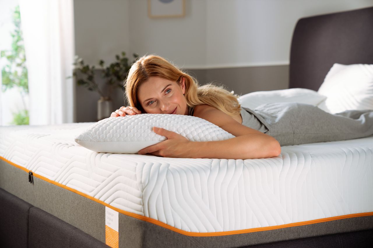 A woman hugging a pillow on a Tempur mattress