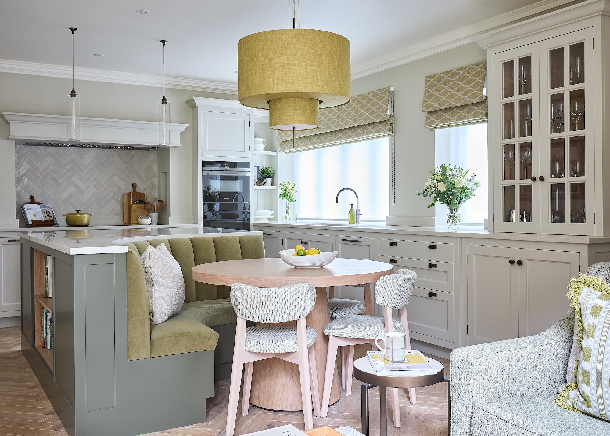 a curved island with an extended dining bench and a pink table next to it.