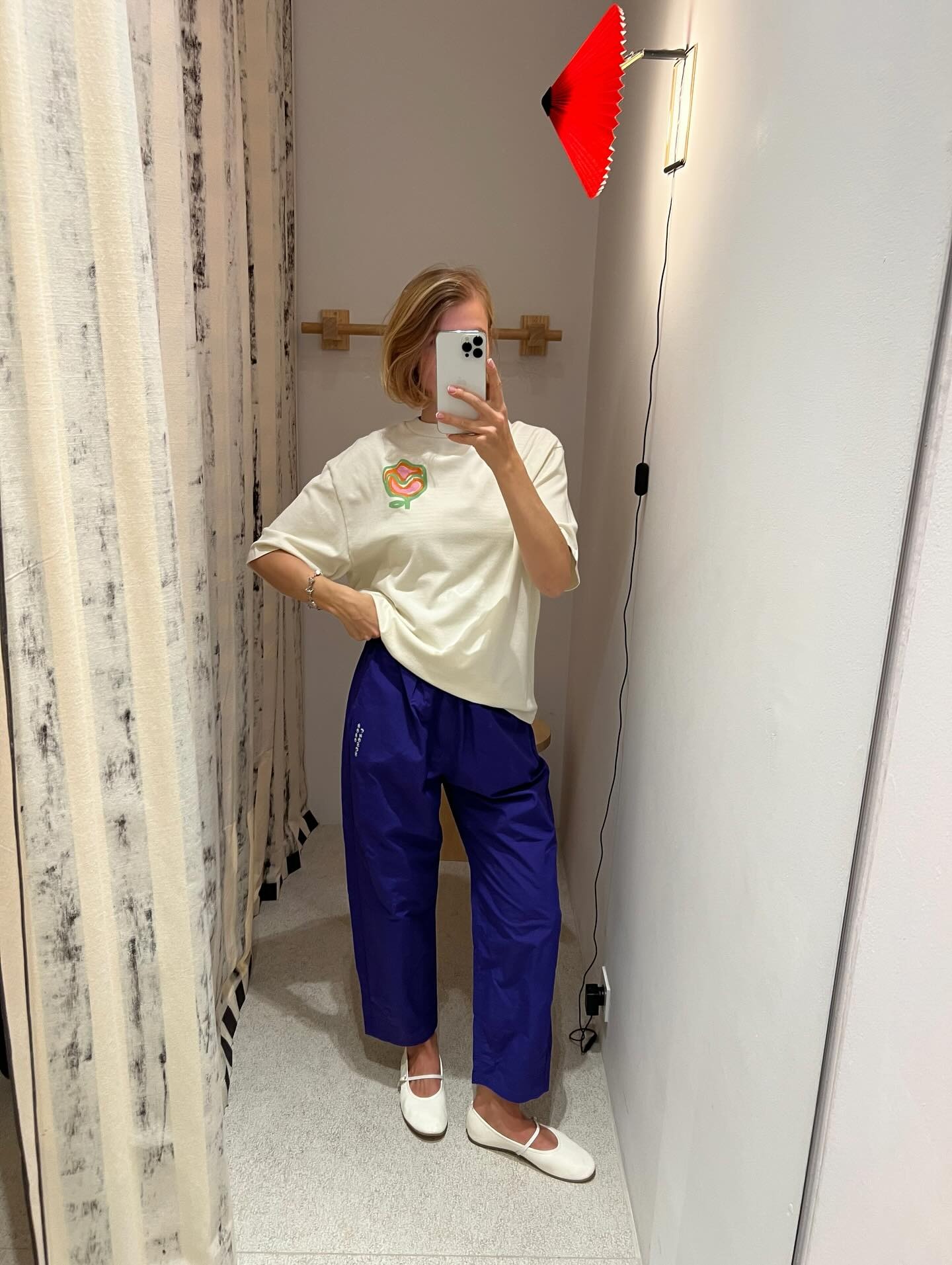 Woman wears purple elastic waistband pants, white t-shirt and white Mary Jane flats.