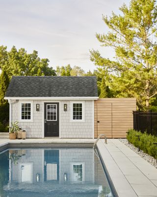 A large pool and sauna built into the backyard of this Ontario home with a shade that has been elevated with outdoor lighting fixtures