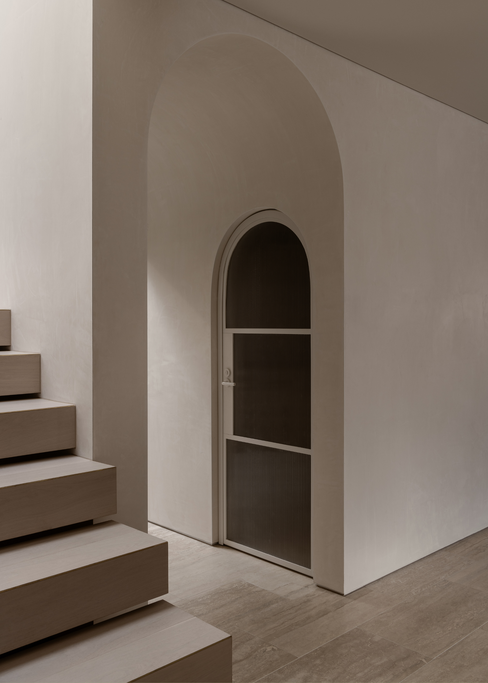 A minimalist staircase by an arched doorway