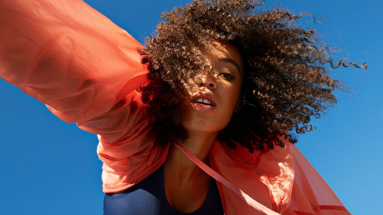 Directly below shot of female athlete with curly hair against clear sky