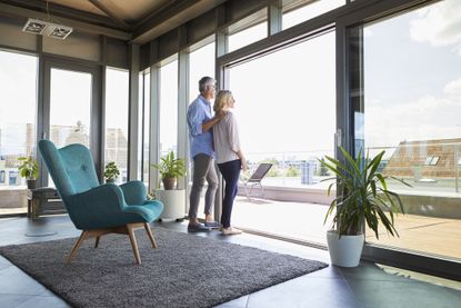 Mature couple looking out of window at home