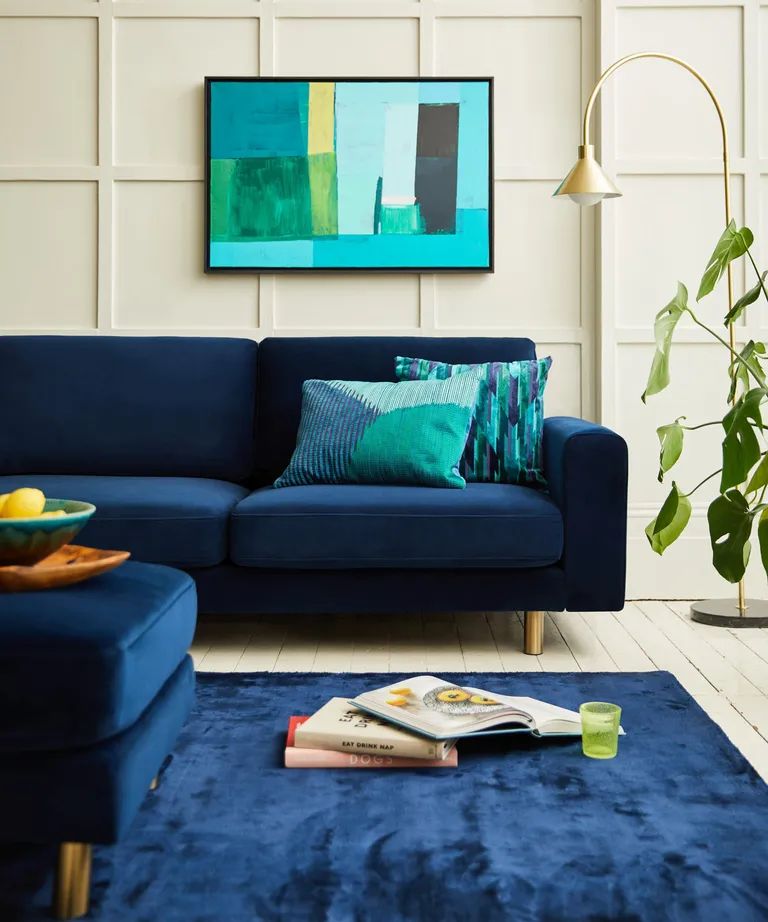 A living room with cream panelled walls and a blue navy velvet sofa