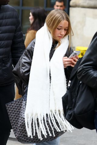 Harper Beckham wears an extra oversize scarf with a Goyard tote while walking in Paris