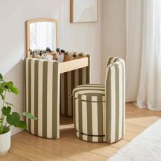 Dressing table in striped fabric in a white bedroom with the lid open and the chair pulled out
