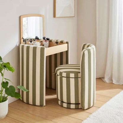 Dressing table in striped fabric in a white bedroom with the lid open and the chair pulled out