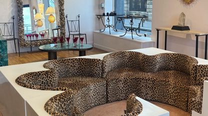 Paris Deco Off 2026 showroom with leopard print modular sofa and antiques in the background