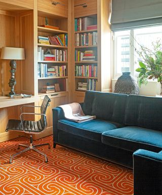 Living room with orange patterned rug and blue sofa