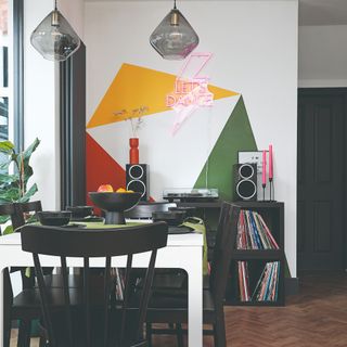 A dining room with a colourful geometric artwork painted on the wall