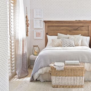 Light bedroom with neutral coastal wallpaper and wooden bed