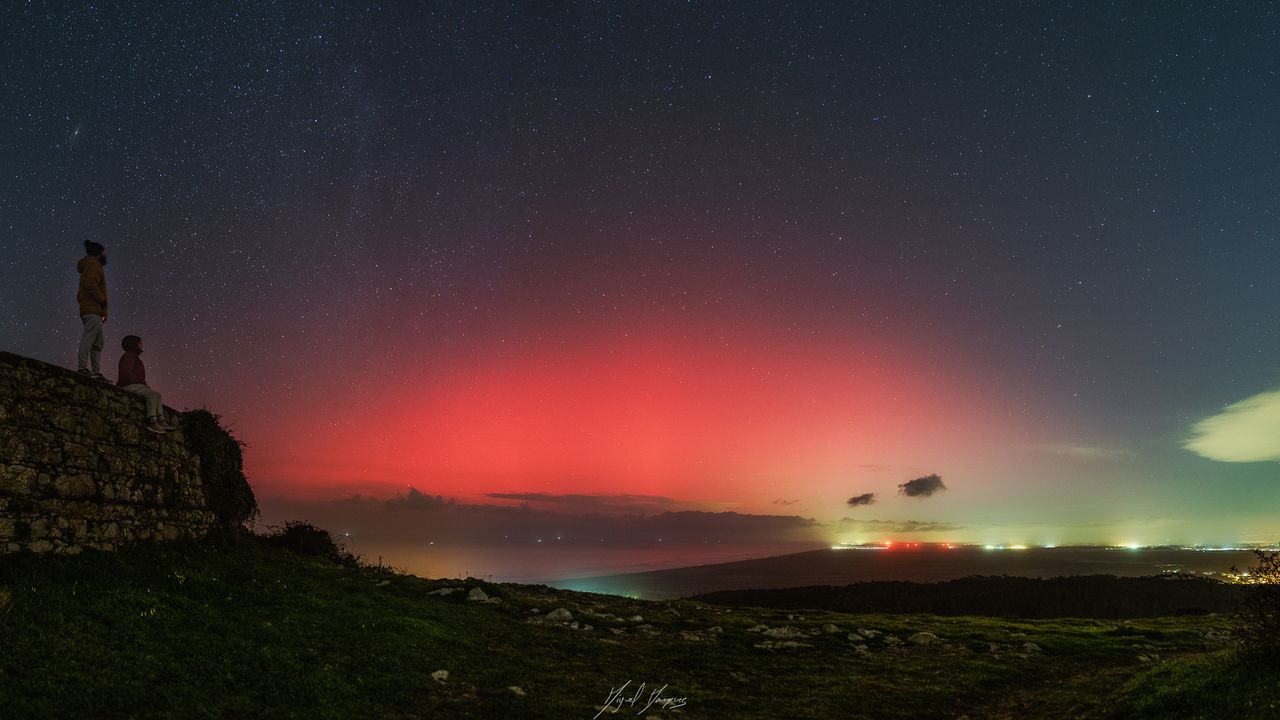 vibrant red light of aurora glows in the sky.