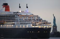 The Queen Mary 2 passes by the Statue of Liberty in New York.