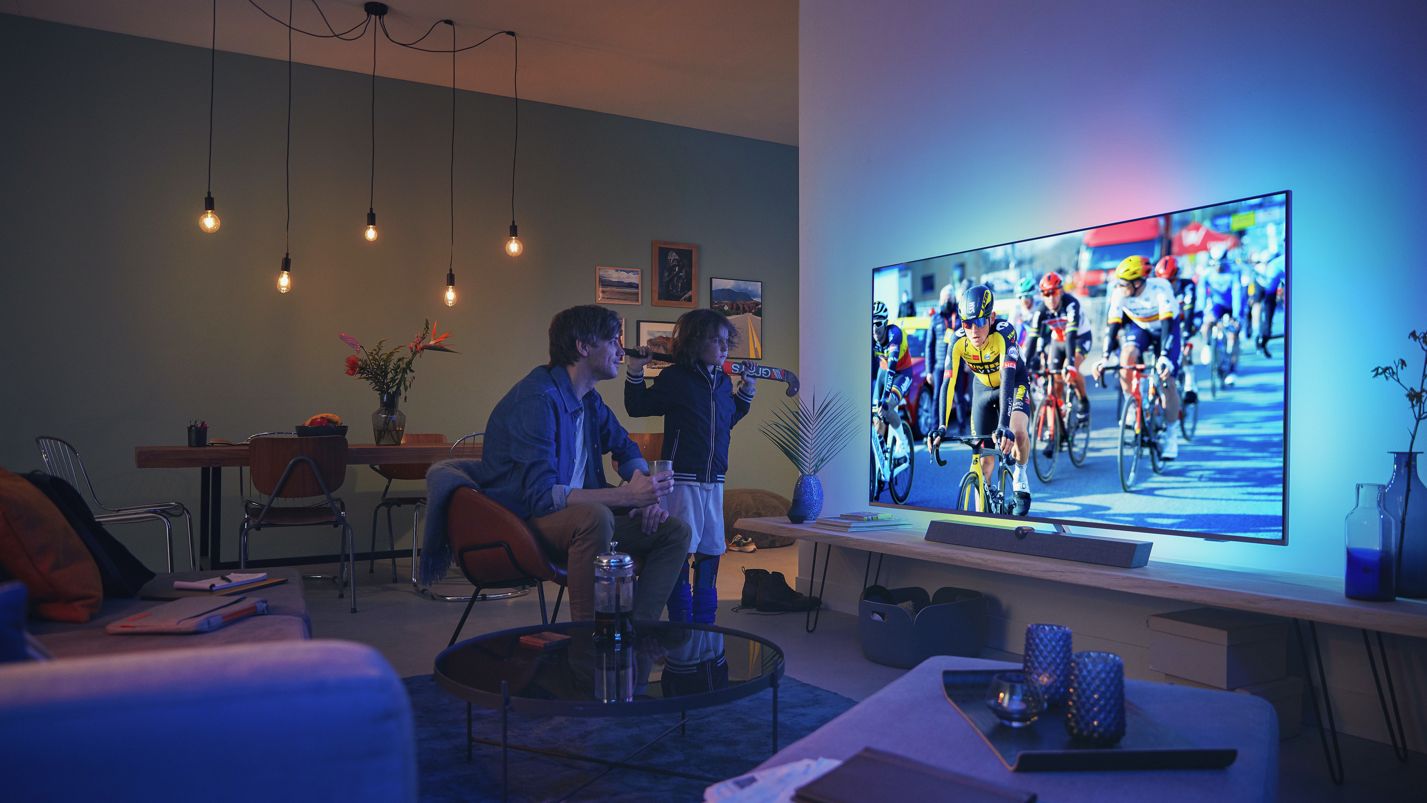 Father and child watching a cycling race on a Philips Ambilight TV