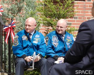 Mark Kelly and Scott Kelly sit outside in NASA uniforms