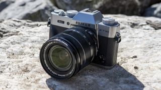 The Fujifilm X-T30 II, one of the best travel cameras, resting on a rock