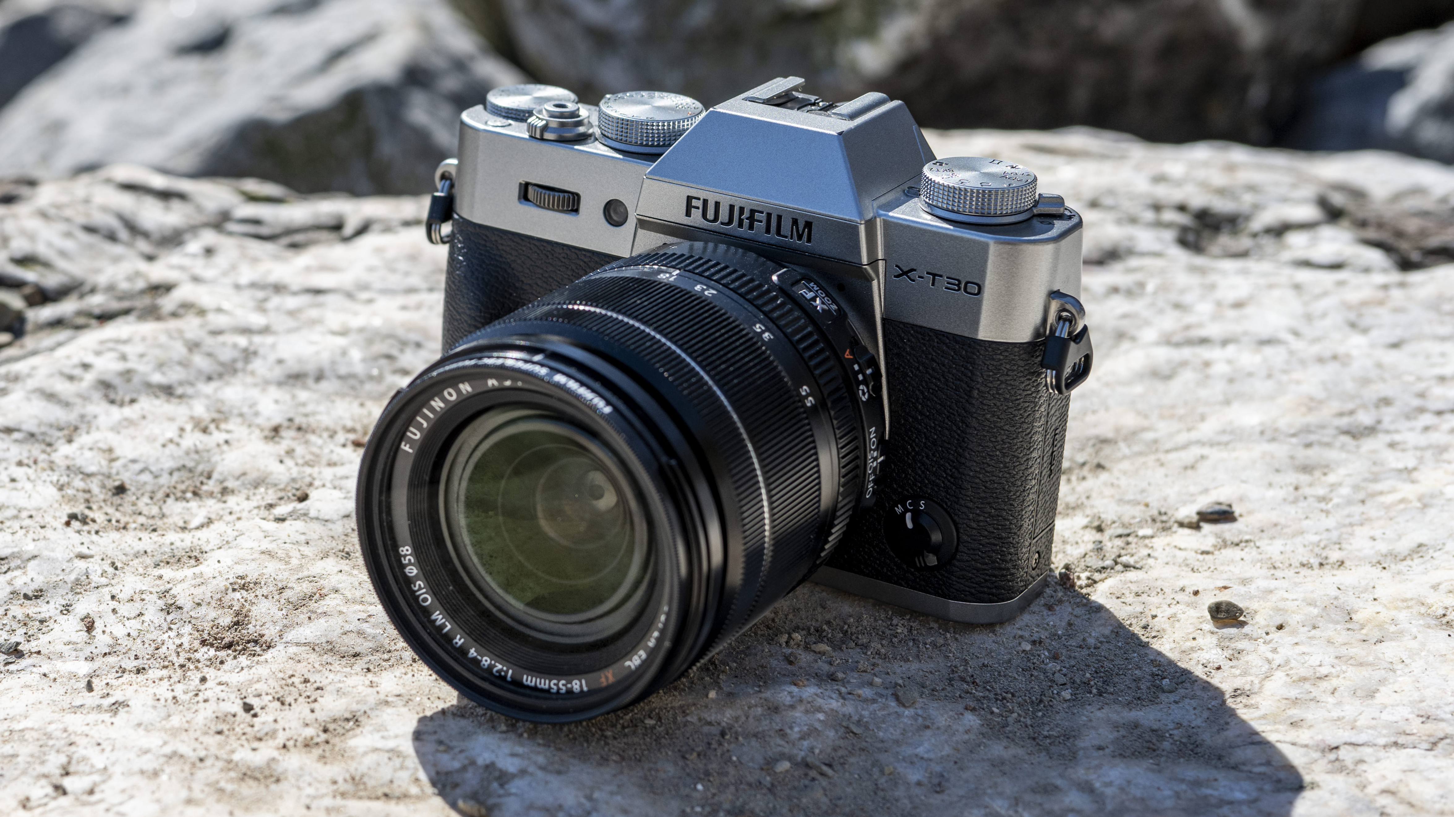 The Fujifilm X-T30 II, one of the best travel cameras, resting on a rock