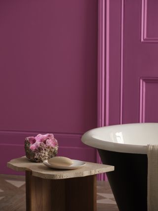 A close-up of a pink crystal on a side table by a bathtub