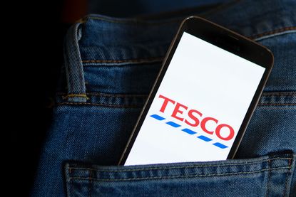 Tesco logo seen displayed on a smartphone sticking out of a jeans pocket