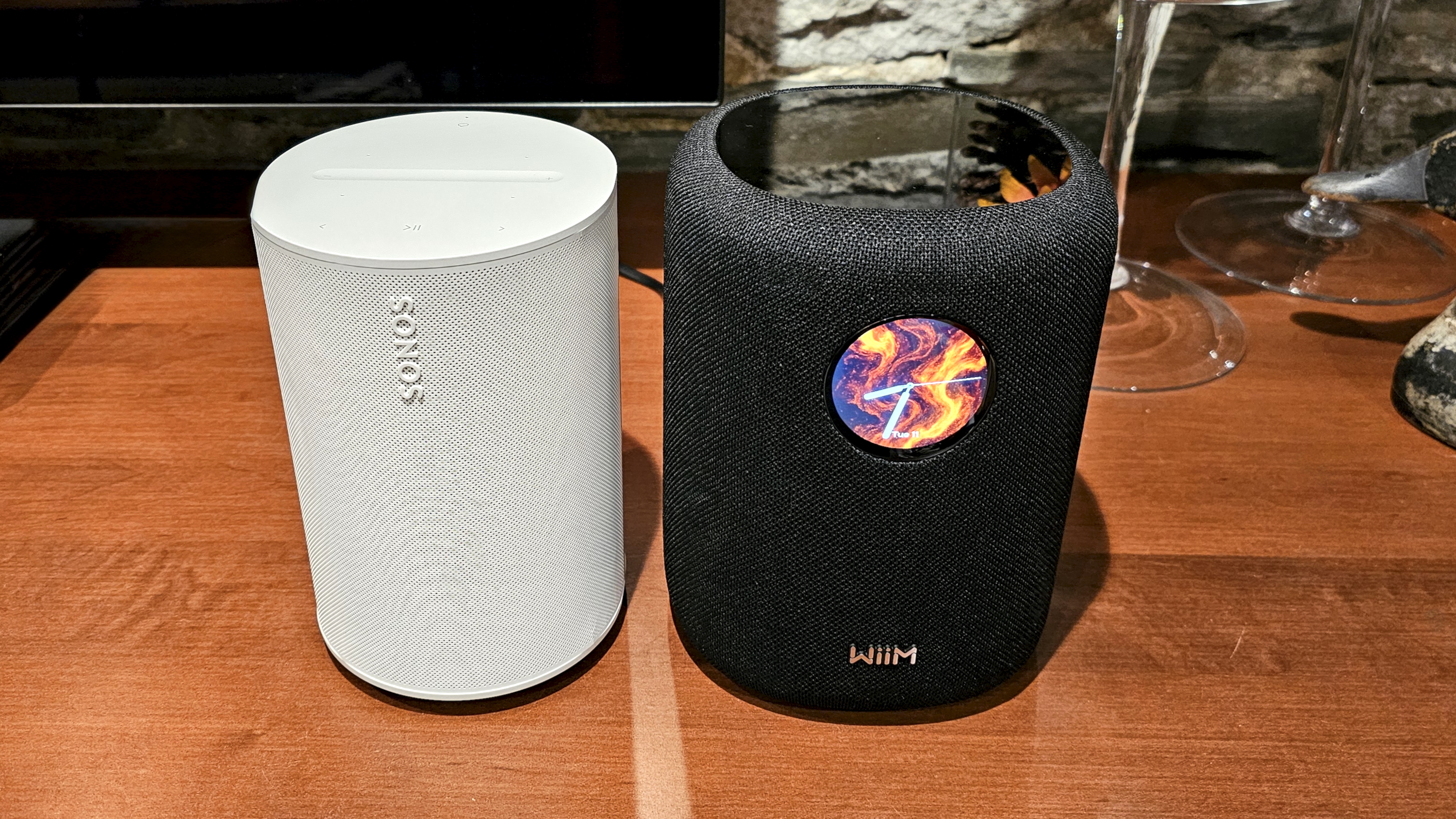 The WiiM Sound, in a home, on a varnished wooden table, showing the illuminated front panel 
