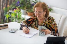 Woman counting money at a table. 