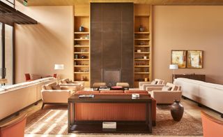 Los Cabos lounge with cream sofas and armchairs, peach walls and brass tiles surrounding fireplace