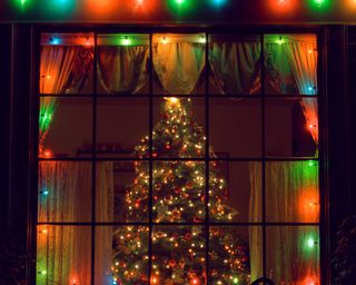 colorful christmas lights and tree through window