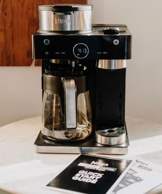 An unboxed Ninja Espresso & Coffee Barista System on white countertop with instruction manual and quick start guide