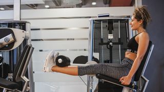 Woman performs leg extension on weights machine