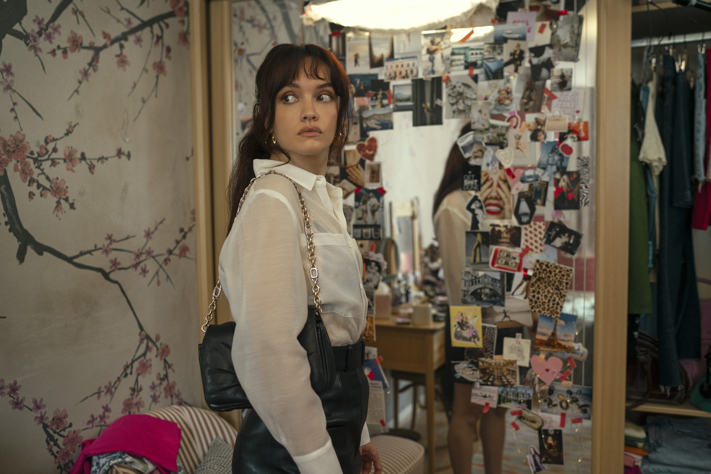 olivia cooke as cherry wearing a white blouse peering over her shoulder looking in a closet in the girlfriend