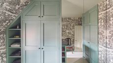 Dressing room with built-in cupboards and mirror tiles on one wall. Grey toile wallpaper.