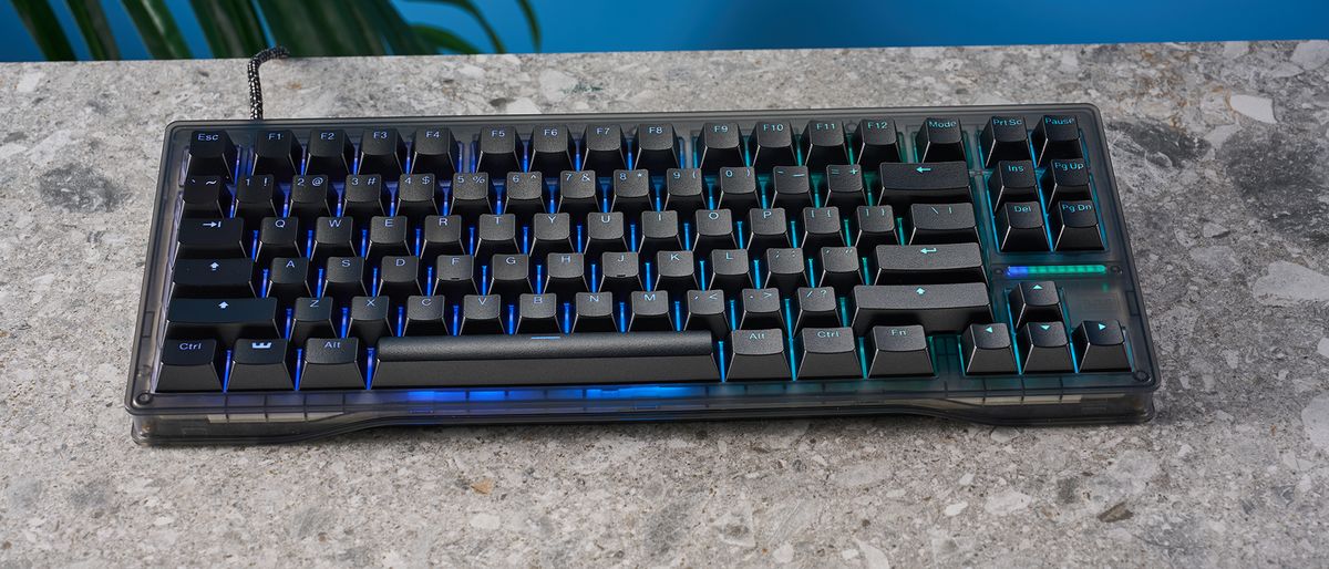 The Wooting 80HE in Ghost PCR case with black keycaps, on a stone surface with a blue background.