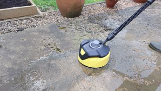 Pressure-washing a driveway using a floor-cleaning attachment.