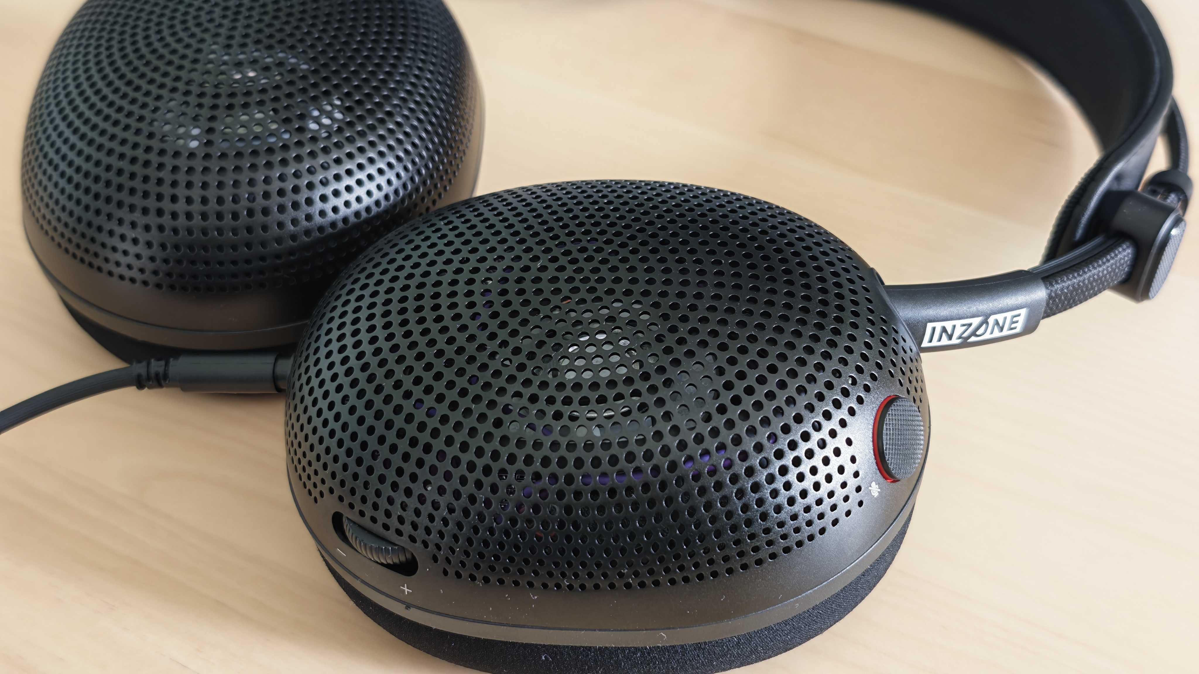 A photo of the Inzone H6 Air gaming headset positioned above a wooden desktop surface.