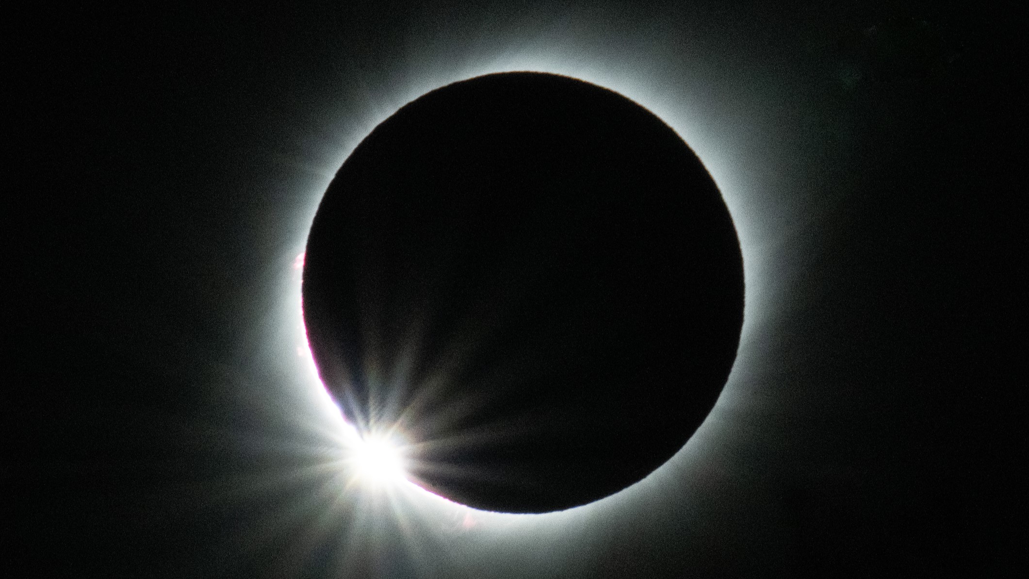 diamond ring effect during total solar eclipse, black circle surrounded by a hazy white light with a distinct bright region looking like a diamond ring