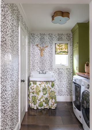 laundry room with black and white animal print wallpaper, green cabinetry, botanical basin curtain, washers, countertop, tiled floor