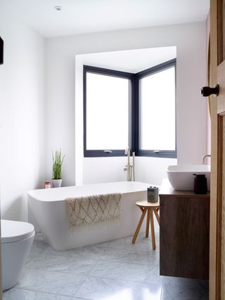 modern bathroom with a freestanding bath, wall hung units, white walls and a wooden table