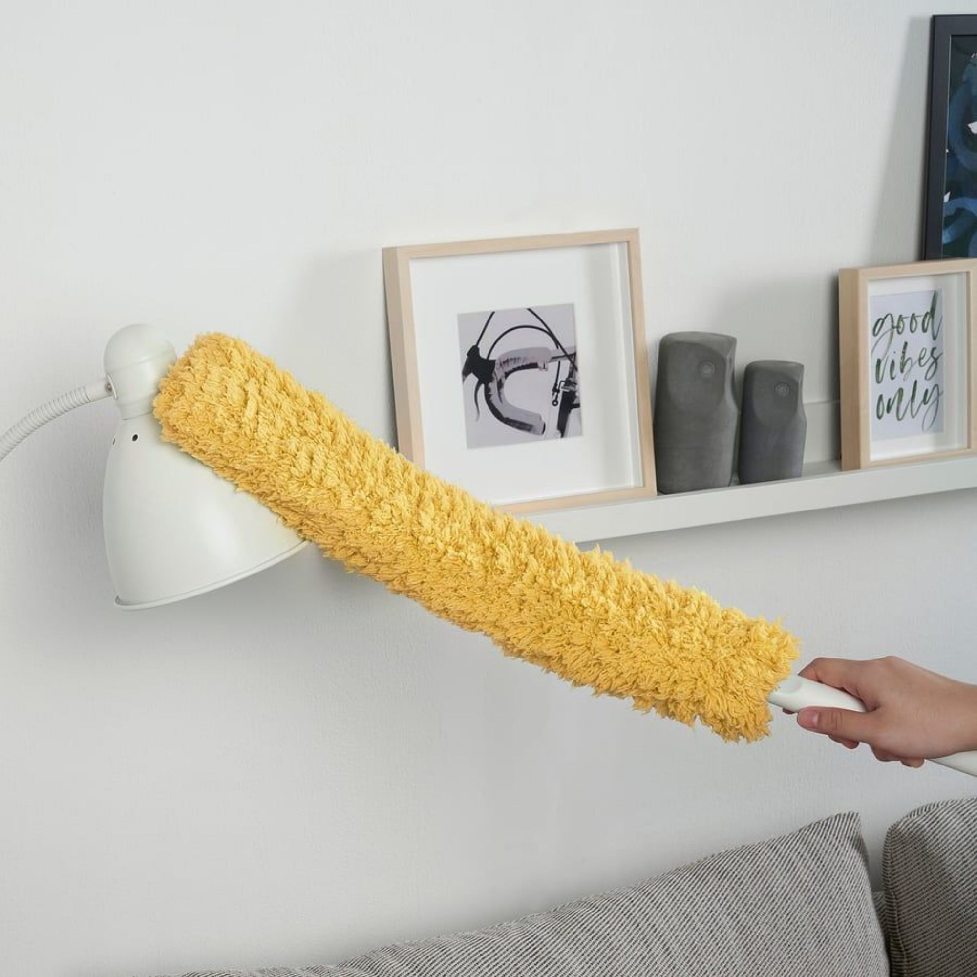 Yellow duster from the IKEA Pepprig Cleaning Set dusting a white lamp in a living room