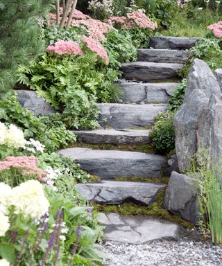 large stone boulder and stone steps surrounded by planting