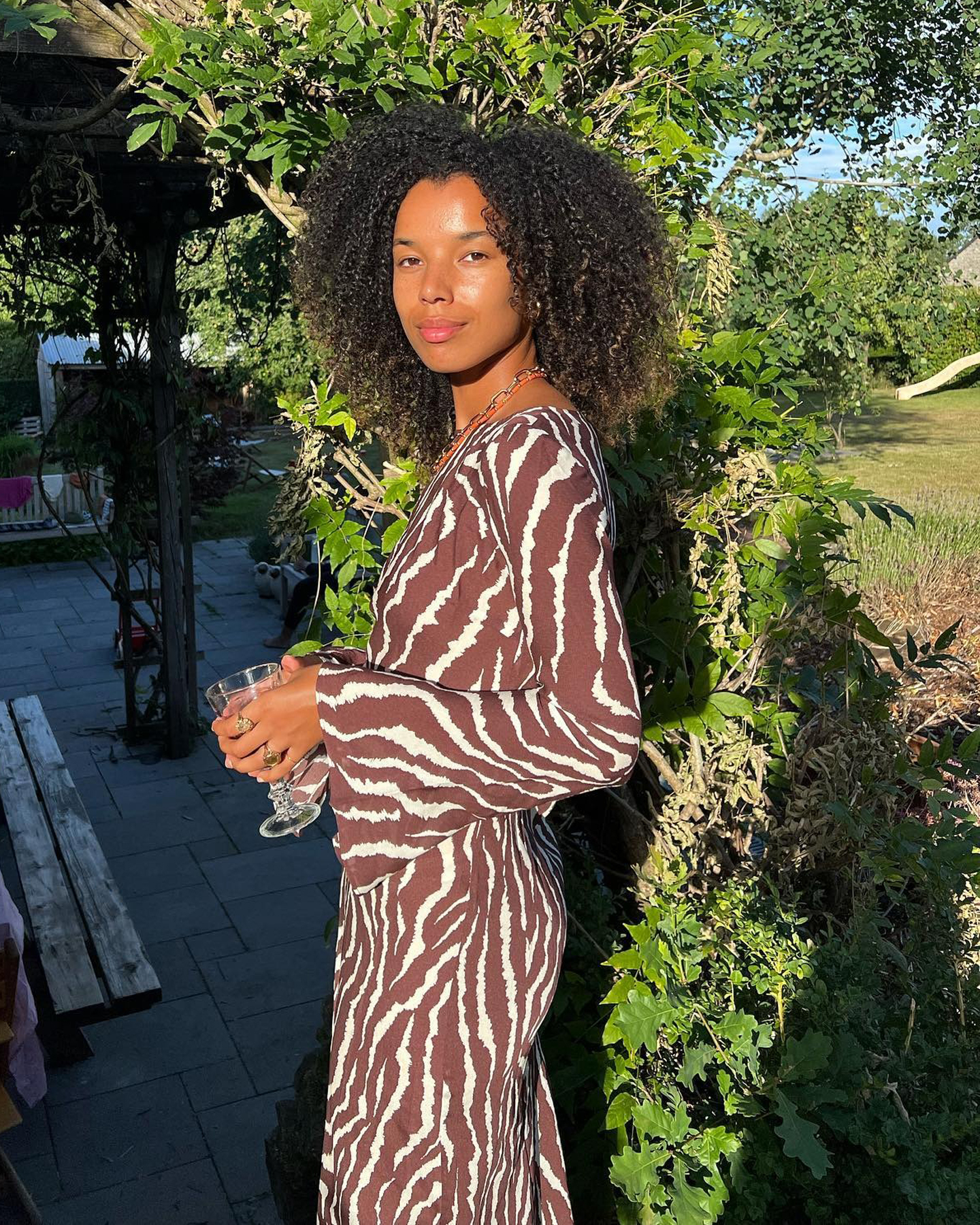 Dutch influencer Fia Hamelijnck poses in a garden wearing a Realisation animal print dress with long sleeves.