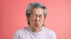 An older man makes a face like he's just tasted a lemon.