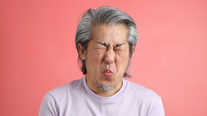 An older man makes a face like he's just tasted a lemon.